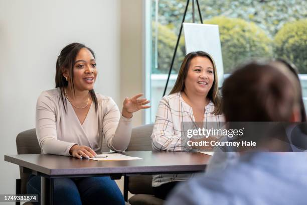 in front of an audience, two women guide a community town hall meeting in a room - diverse town hall meeting stock pictures, royalty-free photos & images