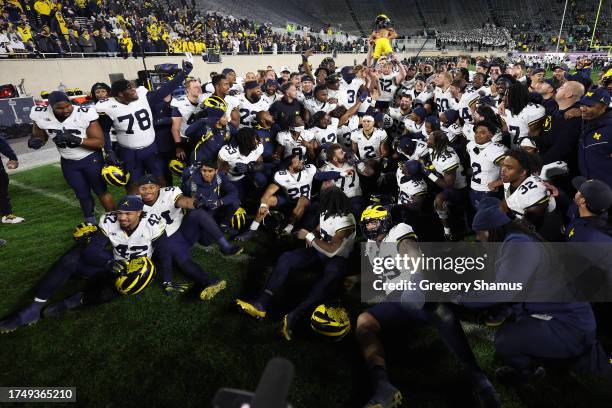 The Michigan Wolverines celebrate with the Paul Bunyan trophy after a 49-0 win over the Michigan State Spartans at Spartan Stadium on October 21,...