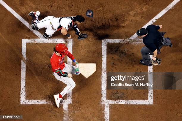 Bryce Harper of the Philadelphia Phillies collides with Gabriel Moreno of the Arizona Diamondbacks to score a run during the first inning in Game...