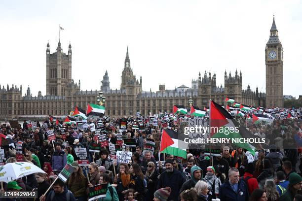 Protesters hold placards and wave Palestinian flags as they walk over Westminster Bridge with the Palace of Westminster, home of the Houses of...