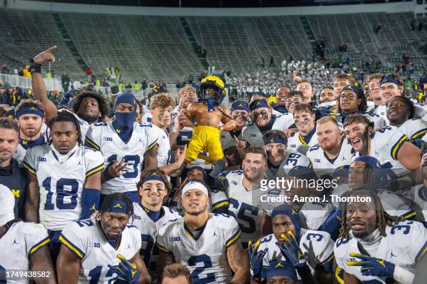 The Michigan Wolverines pose for a team photo with the Paul Bunyan trophy after beating the Michigan State Spartans in a college football game at...