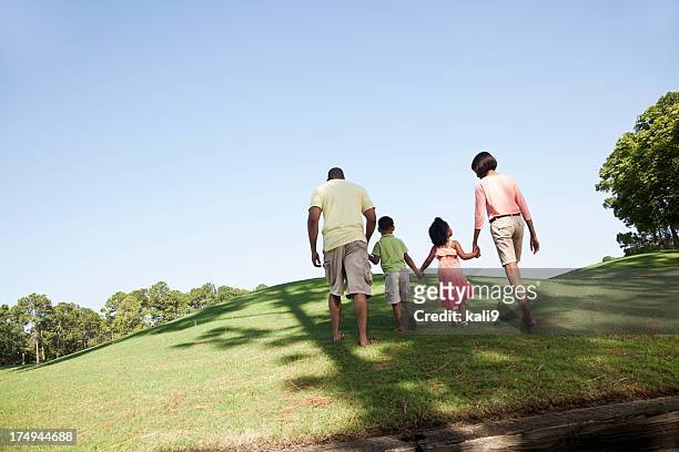 family with two children walking up a hill - four people walking away stock pictures, royalty-free photos & images