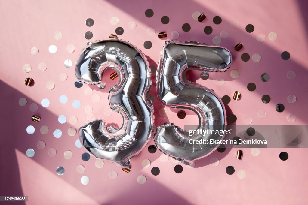 Silver numbers 35 thirty five years balloons in sunlight pink background