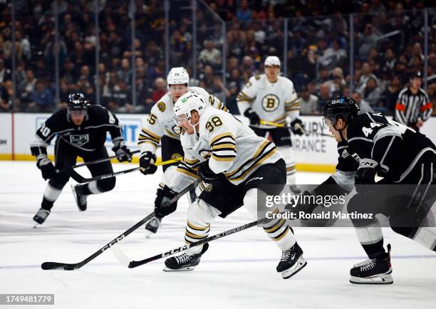 Patrick Brown of the Boston Bruins skates the puck against Mikey Anderson of the Los Angeles Kings in the third period at Crypto.com Arena on October...