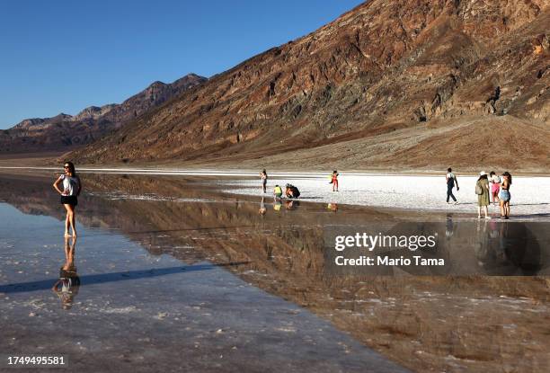 Visitors gather at the sprawling temporary lake at Badwater Basin salt flats, which was caused by flooding in August from Tropical Storm Hilary, at...
