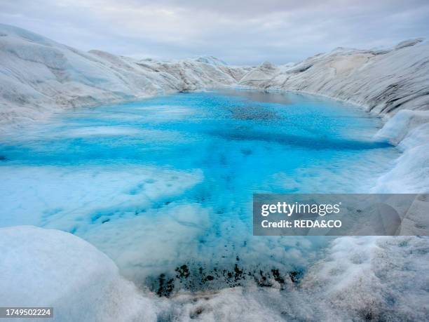 Drainage system with lake on the surface of the ice sheet. The brown sediment on the ice is created by the rapid melting of the ice. Landscape of the...