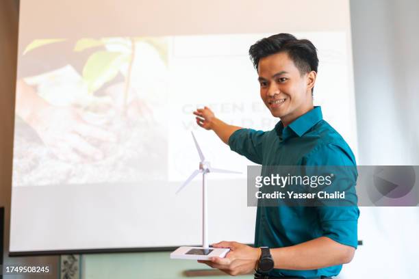 asian man showing wind turbine at business conference - malay archipelago stock pictures, royalty-free photos & images