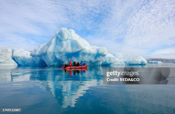 Tourists watching iceberg in the fjord from a zodiac. Landscape in the Johan Petersen Fjord, a branch of the Sermilik Icefjord in the Ammassalik...