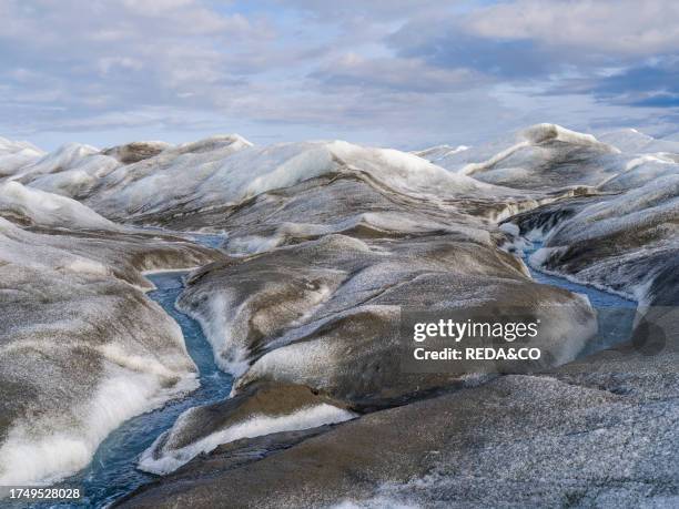 Drainage system on the surface of the ice sheet. The brown sediment on the ice is created by the rapid melting of the ice. Landscape of the Greenland...