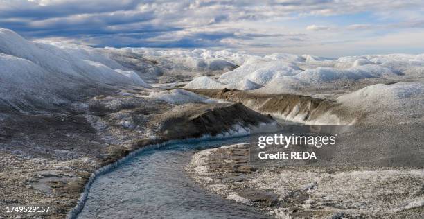 Drainage system on the surface of the ice sheet. The brown sediment on the ice is created by the rapid melting of the ice. Landscape of the Greenland...