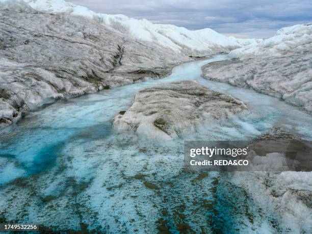 Drainage system on the surface of the ice sheet. The brown sediment on the ice is created by the rapid melting of the ice. Landscape of the Greenland...