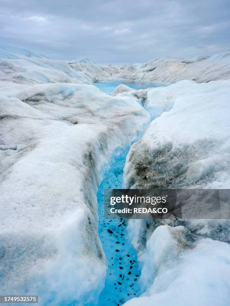 Drainage system on the surface of the ice sheet. The brown sediment on the ice is created by the rapid melting of the ice. Landscape of the Greenland...