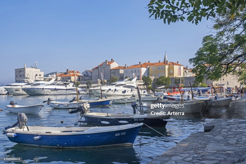 Small fishing boats and motor yachts in marina north of the Old Town city walls of Budva along the Adriatic Sea, Montenegro