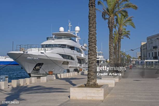 Promenade and motor yachts docked in the seaport. Port of Brindisi on the coast of the Adriatic Sea, Apulia. Puglia region, Southern Italy.