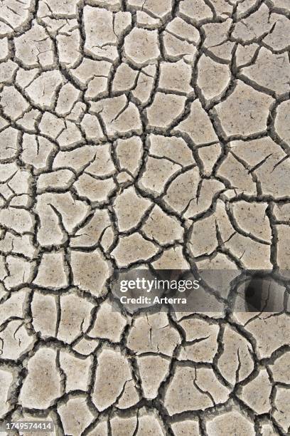 Abstract pattern of dry cracked mud in dried up wetland caused by prolonged drought in summer in hot weather temperatures.