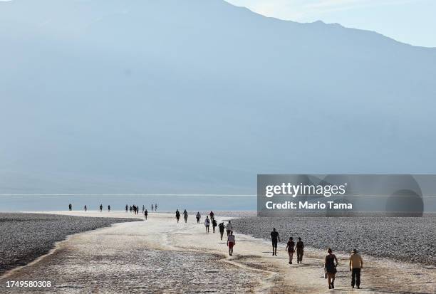 Visitors walk towards the sprawling temporary lake at Badwater Basin salt flats, which was caused by flooding in August from Tropical Storm Hilary,...