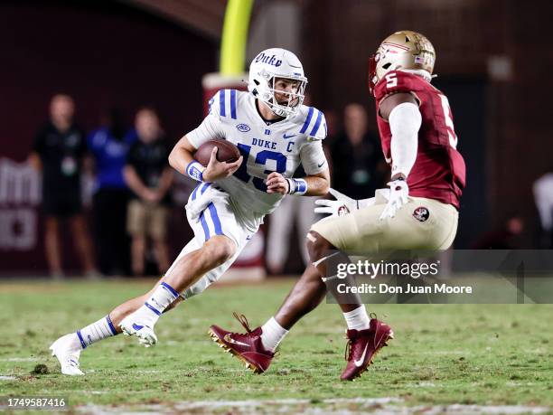 Quarterback Riley Leonard of the Duke Blue Devils avoids being tackled on a run play against Jared Verse of the Florida State Seminoles during the...
