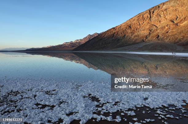 Visitors walk along the sprawling temporary lake at Badwater Basin salt flats, which was caused by flooding in August from Tropical Storm Hilary, at...