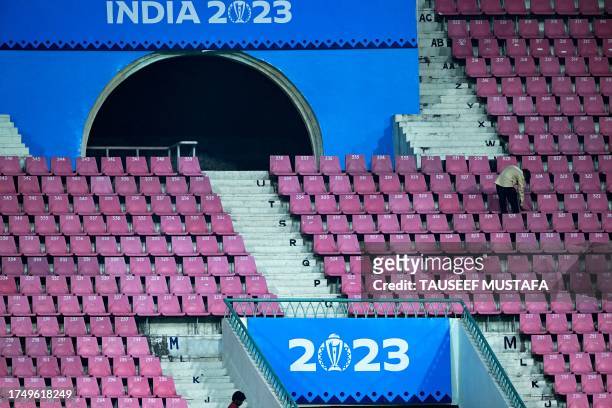 Worker cleans pavillion seats on the eve of the 2023 ICC Men's Cricket World Cup one-day international match between India and England at the Ekana...