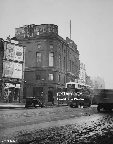 Traffic and pedestrians outside the entrance to the Royal Agricultural Hall, a branch of Lloyds Bank at street level on Upper Street, at the junction...