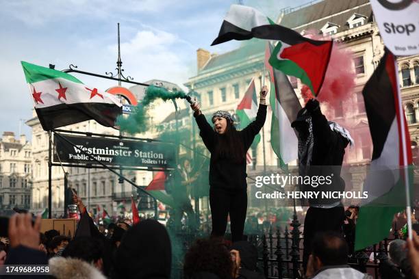 People wave Palestinian and Syrian Opposition flags in Parliament Square after taking part in a 'March For Palestine' in London on October 28 to call...