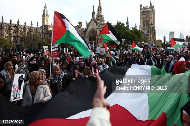 Protesters display a large Palestinian flag in Parliament Square after taking part in a 'March For Palestine' in London on October 28 to call for a...