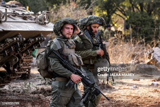 Israeli army soldiers stand by a tracked vehicle at a position in the upper Galilee region of northern Israel near the border with Lebanon on October...