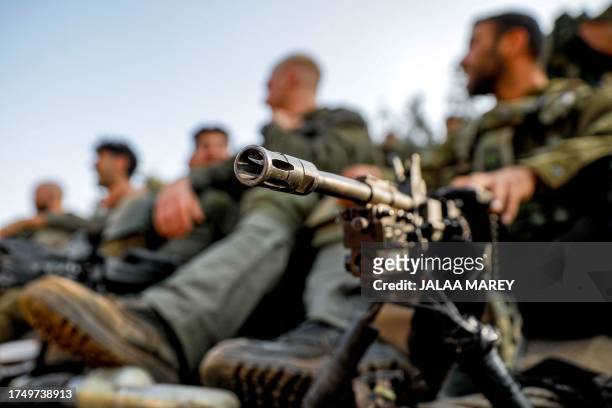 An Israeli army soldier sits by a machine gun deployed on a tripod at a position in the upper Galilee region of northern Israel near the border with...