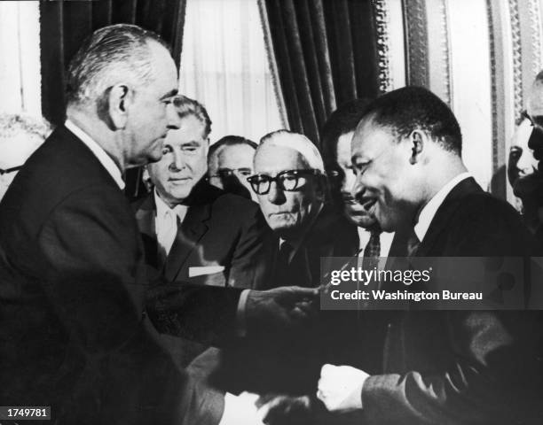 President Lyndon B Johnson hands a pen to civil rights leader Reverend Martin Luther King Jr during the the signing of the voting rights act as...
