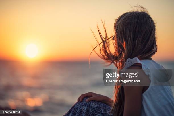 little girl enjoying beautiful sunset on the beach - behind sun stock pictures, royalty-free photos & images