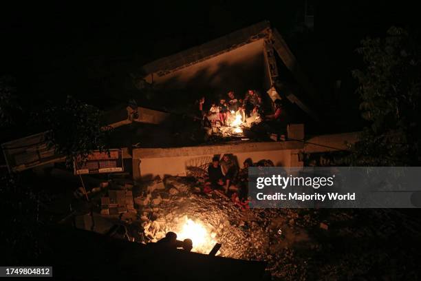 Gaza City, Palestine. 16th May 2023. The Palestinian Nabhan family sits at night under the rubble of their destroyed house near a fire in Jabalia, in...