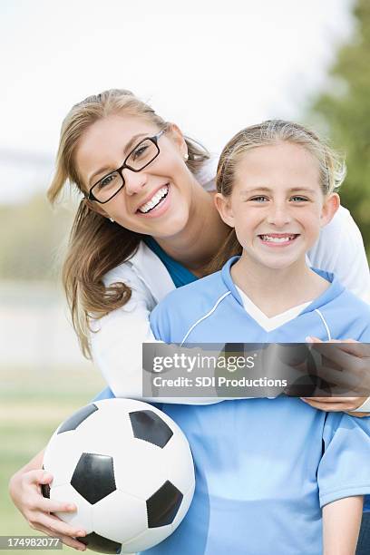 mom posing with daughter before soccer game - soccer mom stock pictures, royalty-free photos & images