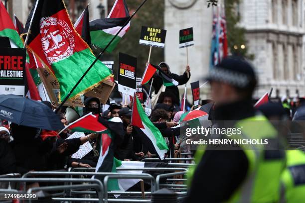 Protesters hold up placards and wave Palestinian flags at the gates of Downing Street after taking part in a 'March For Palestine' in London on...