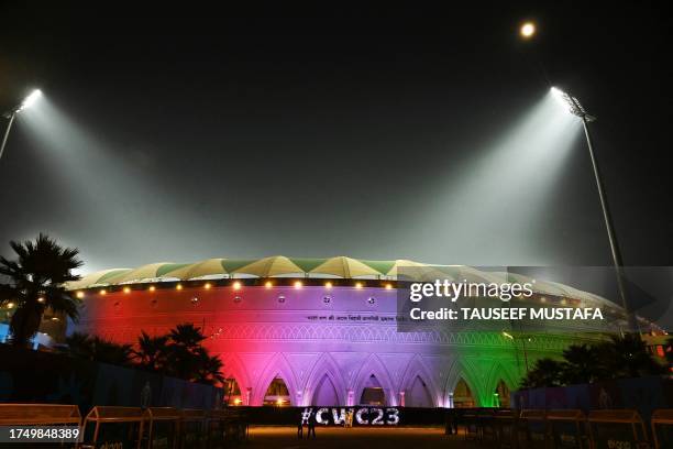 People stand outside the Ekana Cricket Stadium illuminated with India's national flag colours, on the eve of the 2023 ICC Men's Cricket World Cup...