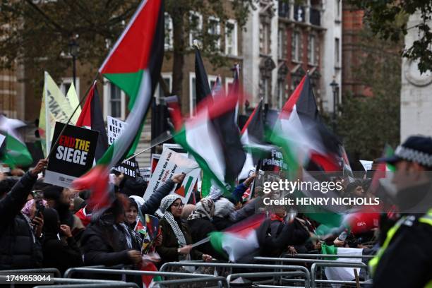 Protesters hold up placards and wave Palestinian flags at the gates of Downing Street after taking part in a 'March For Palestine' in London on...