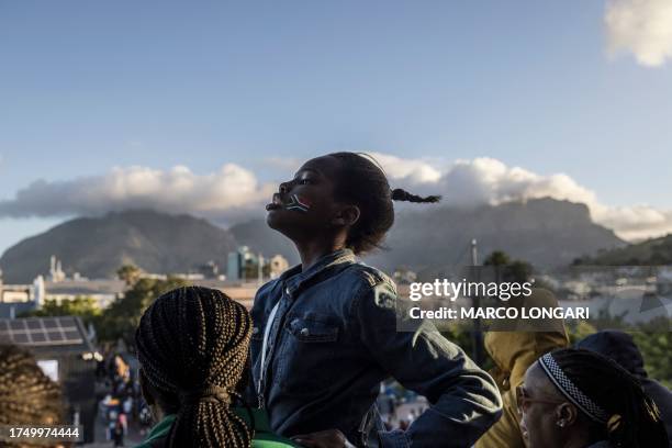 Girl with a South African flag sticker on her cheek is seen backdropped by the iconic Table Mountain among fans gathering at the V&A Waterfront Mall...