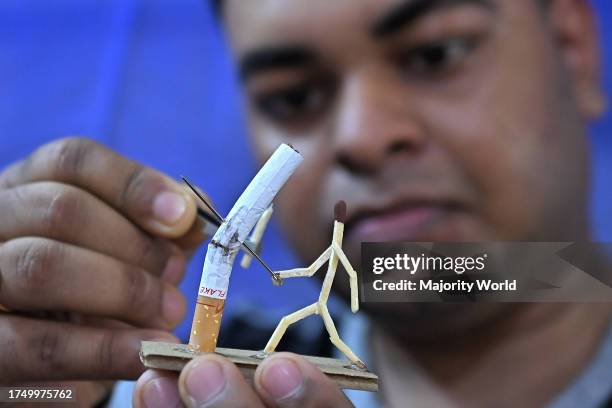 Bijoy Debnath, a 21 year old artist showing his art work created with matchsticks and cigarettes depicting a matchstick man killing a cigarette with...