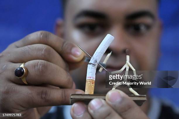 Bijoy Debnath, a 21 year old artist showing his art work created with matchsticks and cigarettes depicting a matchstick man killing a cigarette with...