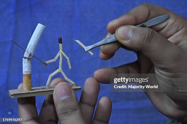 Bijoy Debnath, a 21 year old artist showing his art work created with matchsticks and cigarettes depicting a matchstick man killing a cigarette with...