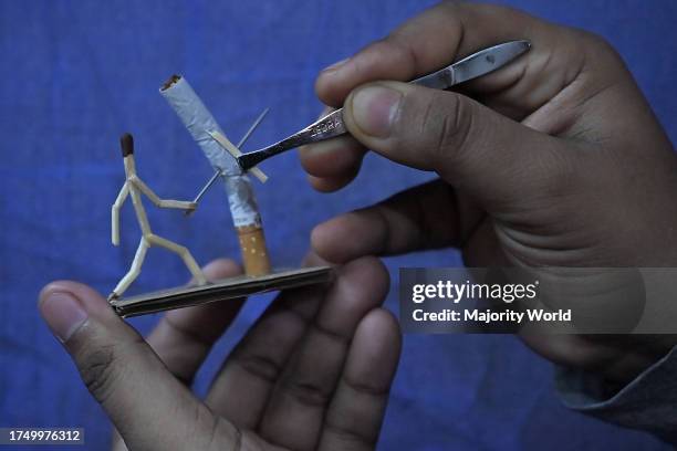 Bijoy Debnath, a 21 year old artist showing his art work created with matchsticks and cigarettes depicting a matchstick man killing a cigarette with...