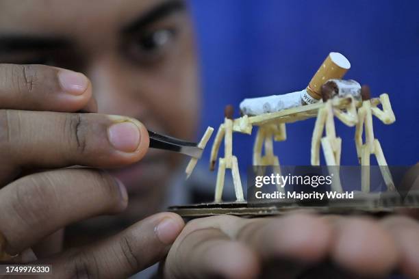 Bijoy Debnath, a 21 year old artist showing his art work created with matchsticks and cigarettes depicting a matchstick man killing a cigarette with...