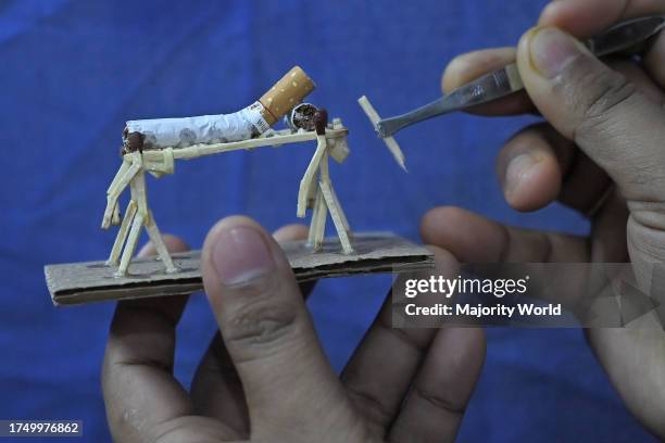 Bijoy Debnath, a 21 year old artist showing his art work created with matchsticks and cigarettes depicting a matchstick man killing a cigarette with...