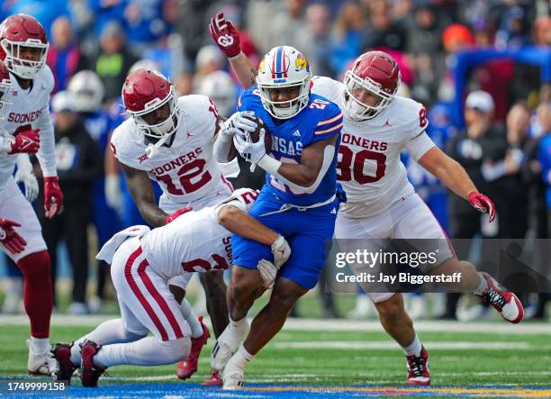 Running back Daniel Hishaw Jr. #20 of the Kansas Jayhawks is tackled by defensive back Billy Bowman Jr. #2, defensive back Key Lawrence, and...