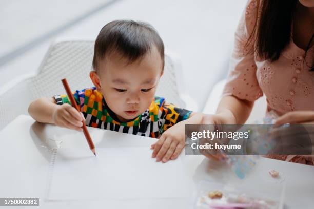 asian toddler having fun drawing at home - child care worker stock pictures, royalty-free photos & images