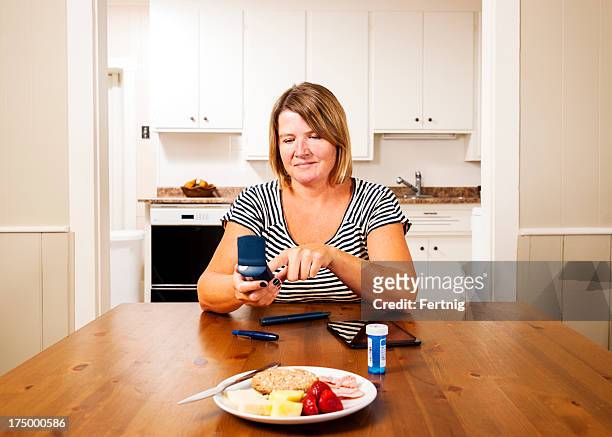 checking blood sugar, glucose levels in the kitchen - diabetes pills stock pictures, royalty-free photos & images