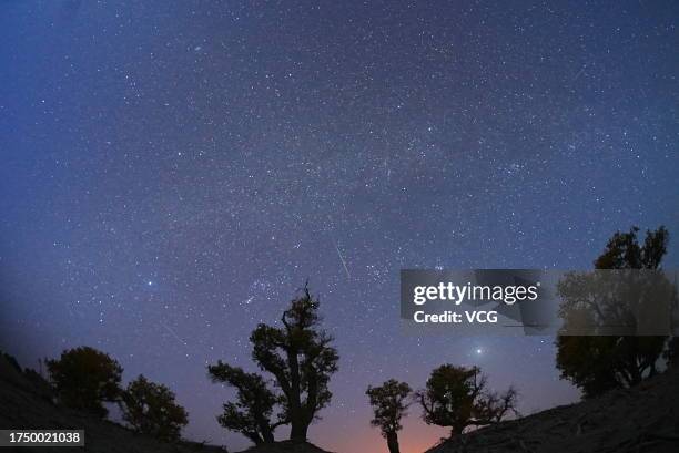 Meteors streak across the sky over a desert during the Orionid meteor shower on October 22, 2023 in Yuli County, Bayingolin Mongol Autonomous...