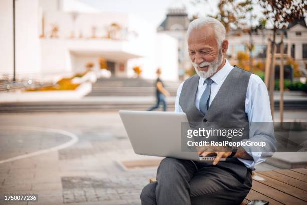 laptop-sitzung eines älteren geschäftsmannes im freien - real businessman isolated no smile stock-fotos und bilder