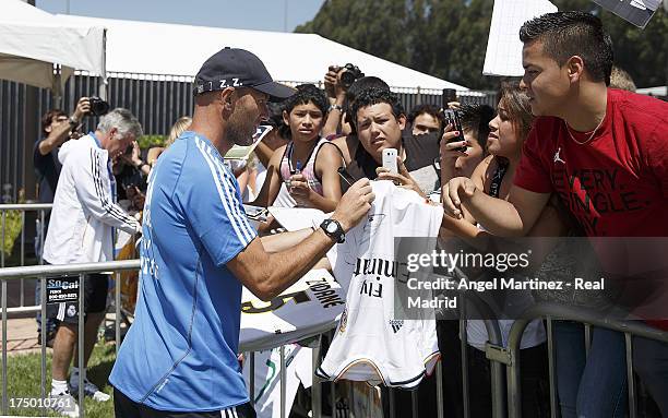 Assistant coach Zinedine Zidane and head coach Carlo Ancelotti of Real Madrid sign autographs to the fans after a training session at UCLA Campus on...