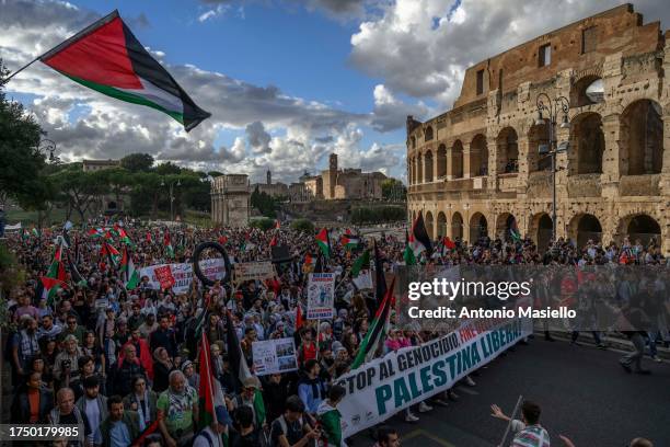 Pro Palestinian supporters hold banners and wave Palestinian flag near the Colosseum during a demonstration to call for a ceasefire in the conflict...