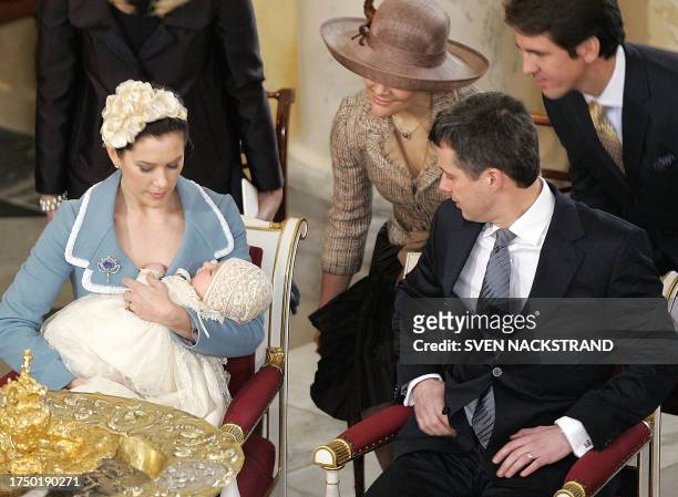 Godfather Crown Prince Pavlos of Greece and Godmother Swedish Crown Princess Victoria look at Prince Christian Valdemar Henri John in the arms of his...